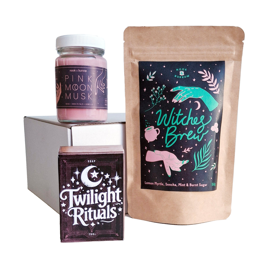 Magical gift set featuring “Witches Brew” tea, “Pink Moon Musk” candle, and “Twilight Rituals” soap, styled with bold, mystical packaging.