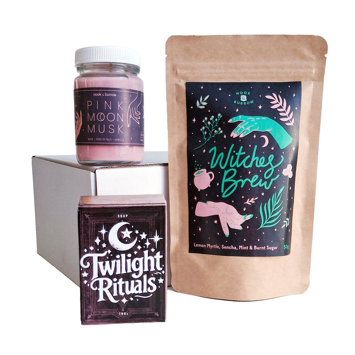 Magical gift set featuring “Witches Brew” tea, “Pink Moon Musk” candle, and “Twilight Rituals” soap, styled with bold, mystical packaging.