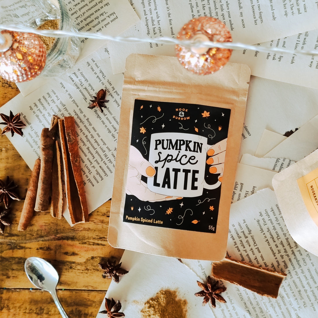 Creamy and Spicy Pumpkin Spiced Latte Blend for the Perfect Autumn Vibe, spices and pumpkin powder surrounding package on a background of pages from a book