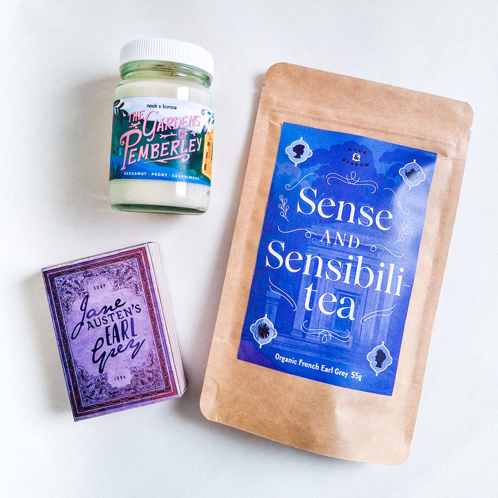 Jane Austen-themed gift set featuring “Sense and Sensibili-tea” organic French Earl Grey tea, “The Gardens of Pemberley” candle, and “Jane Austen’s Earl Grey” soap in elegant purple and blue packaging.
