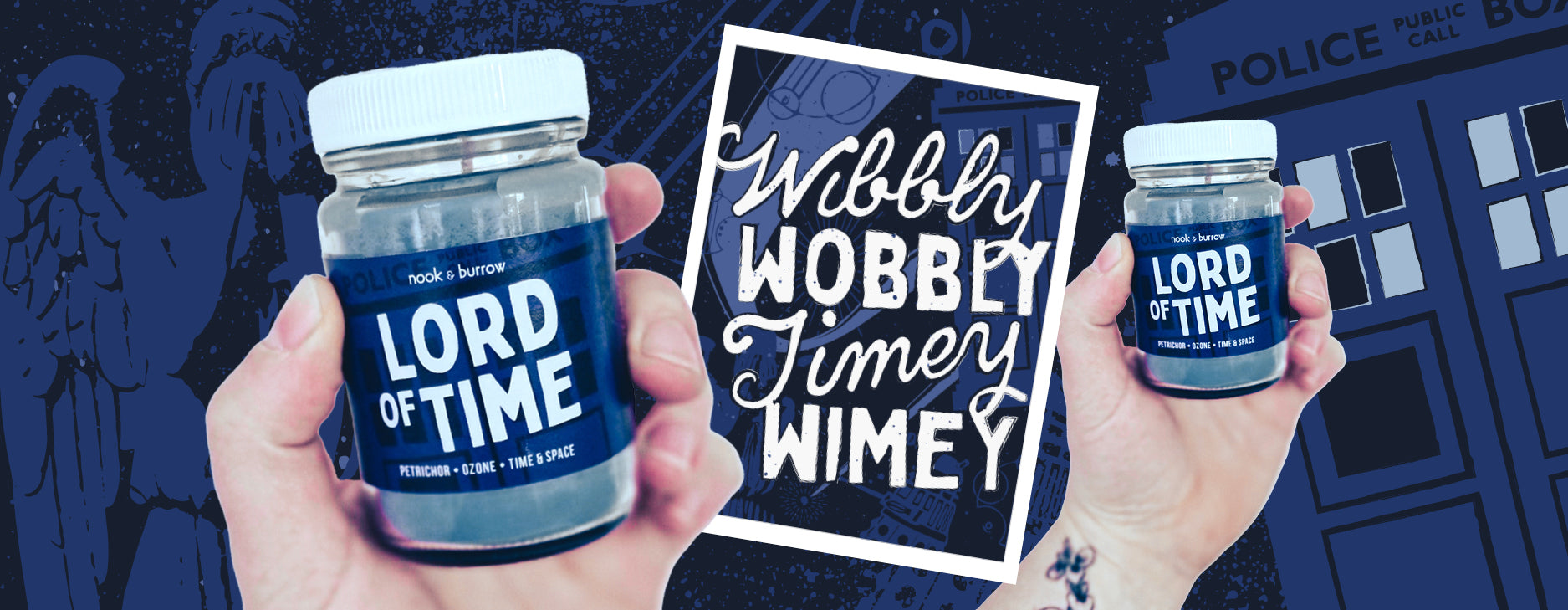 Dr Who candle 'Lord of Time' held up by a hand on the left side and right sides of the banner. With a print in the middle that says 'Wobbly Wobbly Times Wimey'. the overall colour scheme is Police Box Blue and has a Dalek on it.
